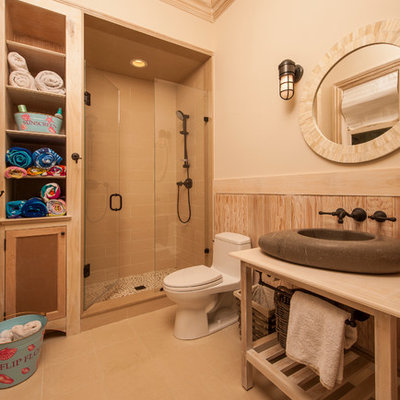 Elegant beige tile alcove shower photo in Raleigh with a vessel sink, furniture-like cabinets, light wood cabinets and a one-piece toilet