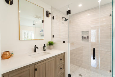 Example of a porcelain tile mosaic tile floor, gray floor and single-sink walk-in shower design in Manchester with medium tone wood cabinets, white walls, an undermount sink, quartzite countertops, a niche and a hinged shower door