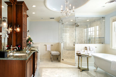 Inredning av ett modernt en-suite badrum, med ett nedsänkt handfat, luckor med infälld panel, skåp i mellenmörkt trä, granitbänkskiva, ett fristående badkar, en hörndusch, en toalettstol med hel cisternkåpa, blå väggar och klinkergolv i porslin