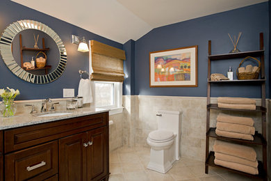 Corner shower - mid-sized traditional master beige tile and ceramic tile ceramic tile corner shower idea in Boston with an undermount sink, raised-panel cabinets, medium tone wood cabinets, quartzite countertops, a one-piece toilet and blue walls
