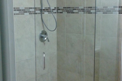 マイアミにあるトランジショナルスタイルのおしゃれな浴室 (コーナー設置型シャワー、ベージュのタイル、ボーダータイル、モザイクタイル、マルチカラーの床、開き戸のシャワー) の写真