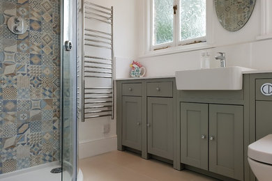 Medium sized mediterranean shower room bathroom in London with shaker cabinets, grey cabinets, a corner shower, a one-piece toilet, multi-coloured tiles, ceramic tiles, multi-coloured walls, porcelain flooring, a built-in sink, quartz worktops, beige floors, a sliding door and white worktops.
