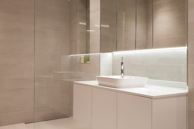 Photo of a medium sized contemporary family bathroom in London with white cabinets, a walk-in shower, a wall mounted toilet, beige tiles, ceramic tiles, beige walls, porcelain flooring, a wall-mounted sink, quartz worktops, beige floors, an open shower and white worktops.