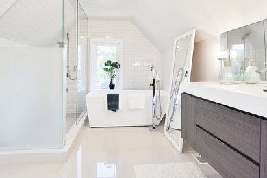 Photo of a medium sized modern ensuite bathroom in Toronto with an integrated sink, flat-panel cabinets, grey cabinets, solid surface worktops, a freestanding bath, a corner shower, a one-piece toilet, beige tiles, ceramic tiles, white walls and ceramic flooring.