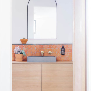 Bild på ett maritimt beige beige badrum, med släta luckor, skåp i ljust trä, orange kakel, vita väggar, ett fristående handfat, träbänkskiva och orange golv