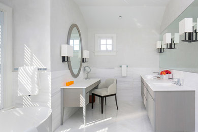 Пример оригинального дизайна: главная ванная комната среднего размера в стиле модернизм с плоскими фасадами, светлыми деревянными фасадами, отдельно стоящей ванной, бежевой плиткой, плиткой мозаикой, белыми стенами, полом из мозаичной плитки, врезной раковиной и столешницей из известняка