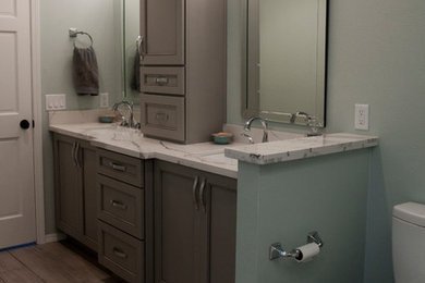 Bathroom - mid-sized contemporary master white tile and ceramic tile ceramic tile and brown floor bathroom idea in Phoenix with recessed-panel cabinets, gray cabinets, a two-piece toilet, blue walls, an undermount sink, granite countertops, a hinged shower door and white countertops