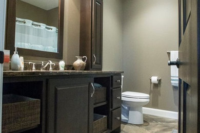Ejemplo de cuarto de baño tradicional de tamaño medio con lavabo integrado, armarios con paneles con relieve, puertas de armario de madera en tonos medios, encimera de laminado, ducha empotrada, paredes grises, suelo vinílico y aseo y ducha