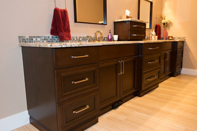 Cette photo montre une grande salle de bain principale tendance en bois foncé avec un placard avec porte à panneau encastré, un sol en bois brun, un lavabo encastré et un plan de toilette en granite.