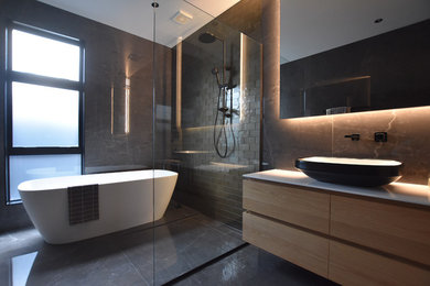 Aménagement d'une salle de bain contemporaine en bois clair avec un espace douche bain, un carrelage marron, aucune cabine et un plan de toilette blanc.