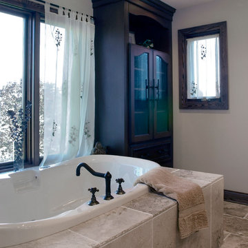 Deck mounted soaking tub in front of a large window with dark wood custom cabine