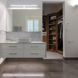 Photo of a mid-sized contemporary bathroom in Melbourne with flat-panel cabinets, white cabinets, an open shower, a two-piece toilet, white tile, ceramic tile, white walls, porcelain floors, a vessel sink, marble benchtops, grey floor and an open shower.