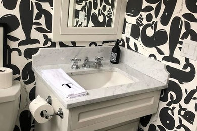 Mid-sized elegant ceramic tile, gray floor, single-sink and wallpaper toilet room photo in New York with shaker cabinets, white cabinets, a two-piece toilet, multicolored walls, an undermount sink, quartz countertops, gray countertops and a freestanding vanity