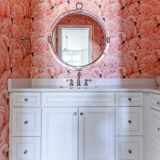 Mid-sized eclectic porcelain tile and white floor bathroom photo in Jacksonville with beaded inset cabinets, a two-piece toilet, an undermount sink, quartz countertops, white cabinets and pink walls