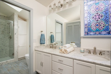 Example of a large beach style master beige tile and ceramic tile ceramic tile bathroom design in San Diego with a drop-in sink, laminate countertops, a one-piece toilet, white walls, recessed-panel cabinets and white cabinets