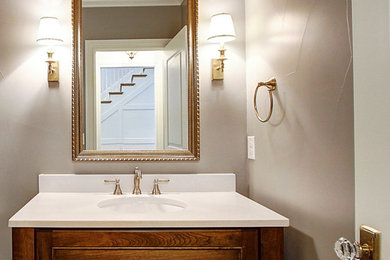 Inspiration för ett stort vintage vit vitt badrum, med luckor med infälld panel, skåp i mellenmörkt trä, en toalettstol med hel cisternkåpa, grå väggar, mellanmörkt trägolv, ett undermonterad handfat, bänkskiva i akrylsten och brunt golv