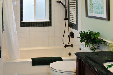 Réalisation d'une salle de bain tradition en bois foncé avec un lavabo encastré, une baignoire en alcôve, un combiné douche/baignoire, un carrelage blanc, un mur vert, un placard avec porte à panneau encastré et un sol multicolore.