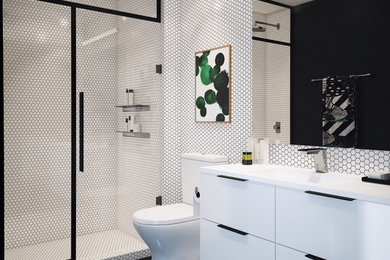 ニューヨークにあるコンテンポラリースタイルのおしゃれなバスルーム (浴槽なし) (フラットパネル扉のキャビネット、白いキャビネット、アルコーブ型シャワー、分離型トイレ、白いタイル、一体型シンク、黒い床、開き戸のシャワー、白い洗面カウンター) の写真