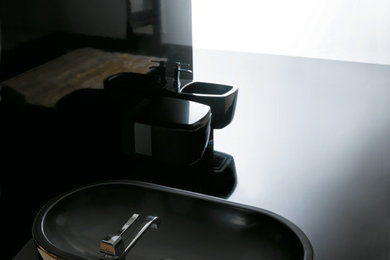 Inspiration for a mid-sized contemporary master black tile and glass sheet concrete floor and black floor bathroom remodel in San Francisco with a vessel sink, open cabinets, black cabinets, a two-piece toilet, black walls, glass countertops and black countertops