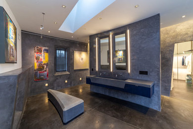 This is an example of an expansive modern ensuite bathroom in New York with a walk-in shower, a wall mounted toilet, grey walls, concrete flooring, a wall-mounted sink, concrete worktops, grey floors, an open shower and grey worktops.