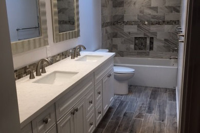 Bathroom - traditional gray tile gray floor bathroom idea in New York with beaded inset cabinets, white cabinets, a two-piece toilet, white walls and an undermount sink
