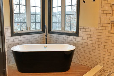 Inspiration for a large modern ensuite bathroom in DC Metro with raised-panel cabinets, white cabinets, a freestanding bath, a corner shower, a two-piece toilet, white tiles, porcelain tiles, white walls, porcelain flooring, a submerged sink, engineered stone worktops, brown floors, a hinged door and white worktops.