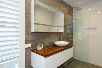 Exemple d'une petite salle de bain principale tendance avec des portes de placard blanches, une douche double, WC à poser, un carrelage gris, des carreaux de céramique, un mur blanc, un sol en carrelage de céramique, une vasque, un plan de toilette en bois, un sol gris et aucune cabine.