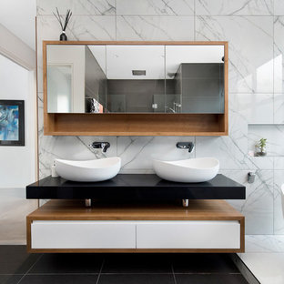 Design ideas for a contemporary bathroom in Canberra - Queanbeyan with flat-panel cabinets, white cabinets, a freestanding tub, white tile, white walls, a vessel sink, black floor and black benchtops.