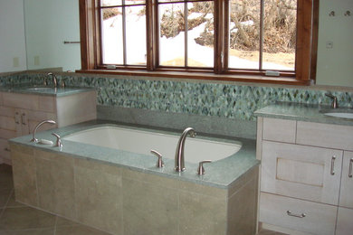 Foto de cuarto de baño actual grande con armarios con paneles lisos, puertas de armario de madera clara, encimera de granito, bañera encastrada sin remate y baldosas y/o azulejos verdes