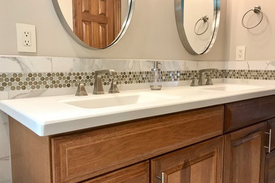 Freestanding bathtub - mid-sized transitional master gray tile and porcelain tile porcelain tile and gray floor freestanding bathtub idea in Other with medium tone wood cabinets, beige walls, an integrated sink, raised-panel cabinets, white countertops, solid surface countertops and a hinged shower door