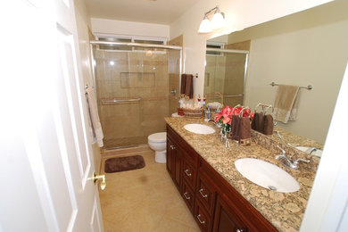 Example of a mid-sized classic beige tile and porcelain tile porcelain tile alcove shower design in Orange County with an undermount sink, raised-panel cabinets, dark wood cabinets, granite countertops, a two-piece toilet and white walls