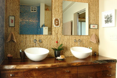 Immagine di una grande stanza da bagno padronale tropicale con lavabo a bacinella, top in legno, piastrelle blu, piastrelle di vetro, pareti marroni, pavimento con piastrelle di ciottoli, ante lisce e ante in legno bruno