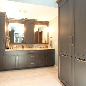 Double vanity with grey stained cabinets and tall linen storage with Brass Hardw