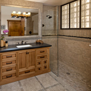 This is an example of a mid-sized asian bathroom in Santa Barbara with an undermount sink, medium wood cabinets, a curbless shower, beige tile, stone tile, limestone floors and recessed-panel cabinets.