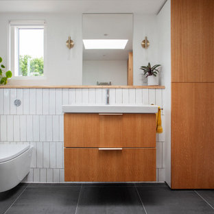 Small midcentury shower room bathroom in London with flat-panel cabinets, light wood cabinets, a built-in shower, a wall mounted toilet, white tiles, ceramic tiles, white walls, ceramic flooring, a console sink, wooden worktops, grey floors, a hinged door, brown worktops, a single sink and a floating vanity unit.