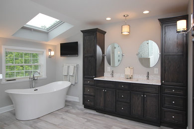 Example of a large transitional master porcelain tile and gray floor freestanding bathtub design in Other with recessed-panel cabinets, dark wood cabinets, white walls, an undermount sink and granite countertops