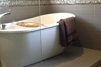 Ejemplo de cuarto de baño principal moderno grande con puertas de armario marrones, encimera de vidrio, bañera exenta, ducha abierta, baldosas y/o azulejos grises, baldosas y/o azulejos en mosaico, paredes grises y suelo de baldosas de cerámica