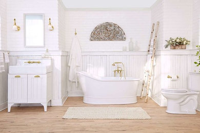 Großes Landhaus Badezimmer En Suite mit weißen Schränken, freistehender Badewanne, Wandtoilette mit Spülkasten, weißer Wandfarbe, braunem Holzboden, Einbauwaschbecken, Marmor-Waschbecken/Waschtisch und beigem Boden in New York