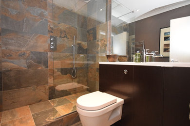 Modelo de cuarto de baño contemporáneo de tamaño medio con ducha abierta, sanitario de pared, paredes marrones, suelo de baldosas de cerámica, lavabo encastrado y ducha abierta