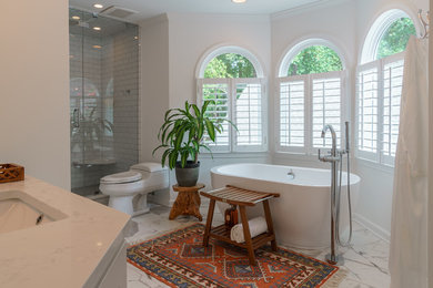 Example of a mid-sized transitional master white tile and ceramic tile ceramic tile and white floor bathroom design in Atlanta with shaker cabinets, white cabinets, a one-piece toilet, white walls, an undermount sink, solid surface countertops and a hinged shower door