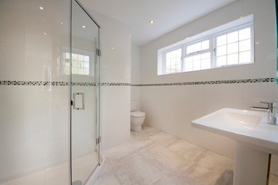 Photo of a medium sized modern family bathroom in West Midlands with glass-front cabinets, a corner shower, a one-piece toilet, white tiles, white walls, marble flooring and a pedestal sink.