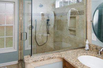 ローリーにある高級なコンテンポラリースタイルのおしゃれな浴室 (アンダーカウンター洗面器、レイズドパネル扉のキャビネット、御影石の洗面台、アルコーブ型シャワー、ベージュのタイル、磁器タイル) の写真