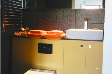 This is an example of a medium sized modern shower room bathroom in Valencia with flat-panel cabinets, a freestanding bath, black tiles, black walls, a vessel sink, orange cabinets and porcelain flooring.