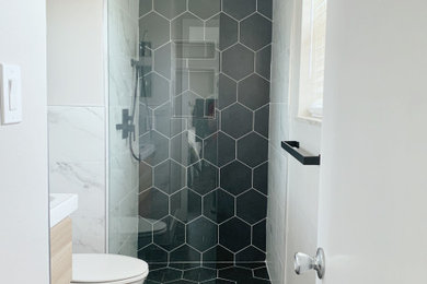 Example of a small minimalist master white tile and porcelain tile single-sink doorless shower design in Denver with flat-panel cabinets, light wood cabinets, white countertops and a floating vanity