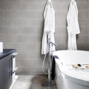Freestanding bathtub - modern concrete floor freestanding bathtub idea in Austin with gray cabinets