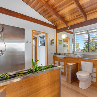 Inspiration for a modern 3/4 bathroom in Other with shaker cabinets, medium wood cabinets, a corner shower, a two-piece toilet, metal tile, white walls, light hardwood floors, a drop-in sink, stainless steel benchtops and an open shower.