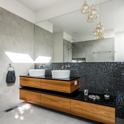 Trendy master black tile and mosaic tile ceramic tile bathroom photo in Melbourne with a vessel sink, flat-panel cabinets, medium tone wood cabinets and white walls