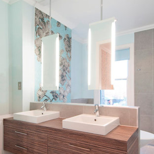Photo of a large contemporary bathroom in London with flat-panel cabinets, medium wood cabinets, wooden worktops, grey floors, brown worktops, double sinks, a floating vanity unit, a freestanding bath, a wall mounted toilet, grey tiles, mosaic tiles, blue walls, porcelain flooring, a console sink and an open shower.
