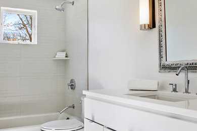 Example of a mid-sized transitional 3/4 gray tile and porcelain tile porcelain tile and white floor bathroom design in New York with flat-panel cabinets, white cabinets, a two-piece toilet, white walls, an undermount sink, solid surface countertops and white countertops