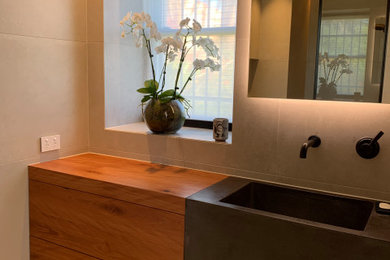 コンテンポラリースタイルのおしゃれなマスターバスルーム (家具調キャビネット、コンクリートの洗面台) の写真